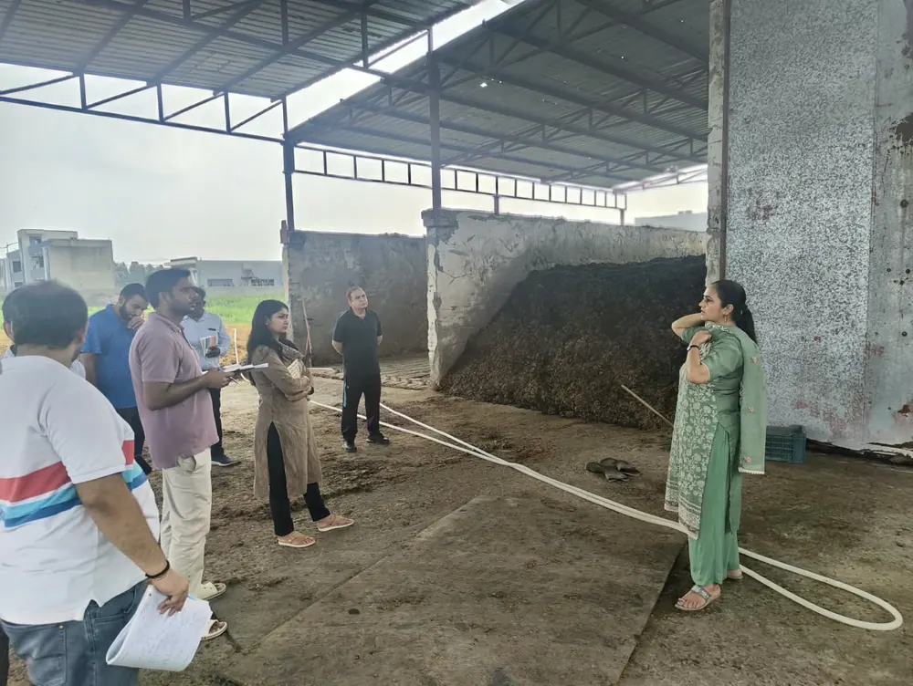 Group inside the covered composting shed looking at finished dark compost